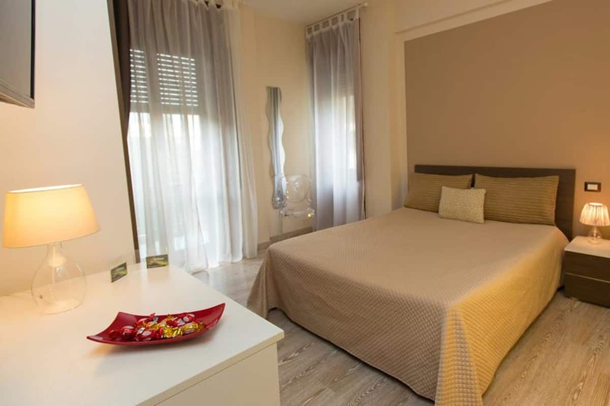 Une chambre d’hôtel avec un lit, des tables de chevet, un bureau et une chaise.