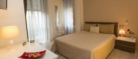 A hotel room with a bed, bedside tables, a desk, and a chair.
