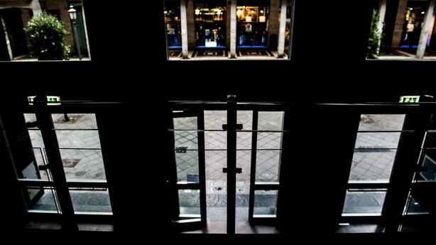 Vista do interior de um edifício, através de uma porta de vidro, para a rua.