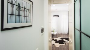 A hallway with a framed abstract artwork, a cowhide rug, and a modern pendant light. - Apartment Horodotska 4 (Lviv)