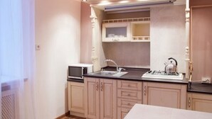 A compact kitchen with a sink, stove, and microwave. - Apartment Horodotska 4 (Lviv)