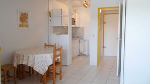 A compact kitchen with a dining area, a refrigerator, and a cabinet.