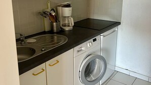 A kitchen with a microwave, coffee maker, sink, and washing machine.