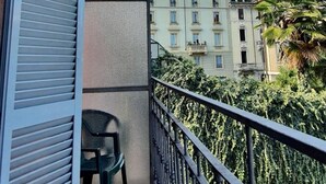 A balcony with a view of a building and a palm tree. - Hotel Mondial (Milan)