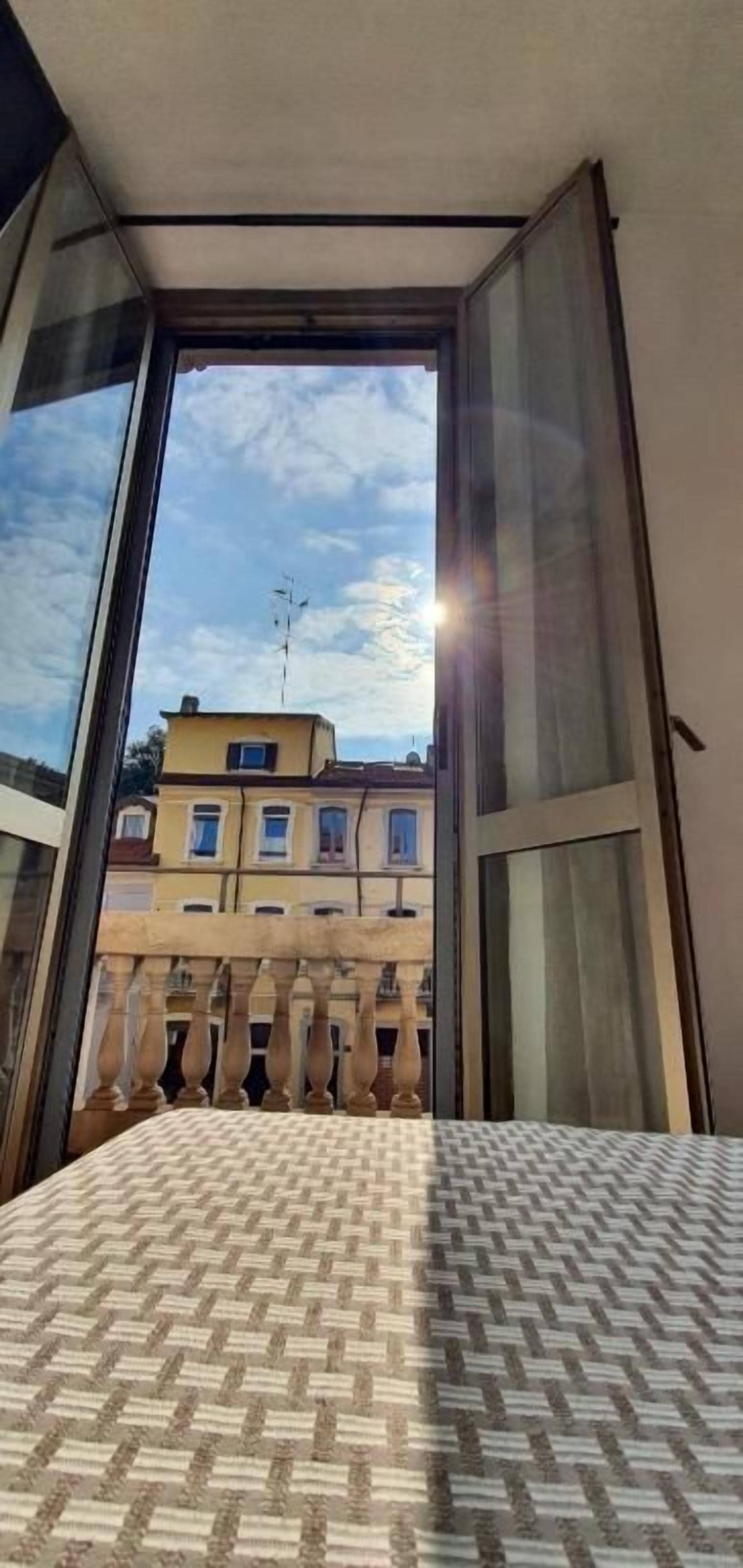 Une fenêtre ouverte donnant sur un immeuble et un balcon.
