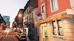 A hotel with a red facade, a sign indicating it is a hotel, and a storefront with a sign that reads "Hotel Mondial." - Hotel Mondial (Milan)