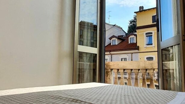 A hotel room with a large window, a bed, and a mounted television. - Hotel Mondial (Milan)