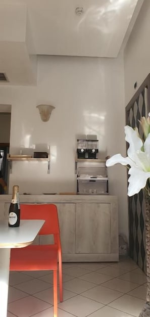 A modern kitchen with a built-in oven, a wine bottle on the counter, and a red chair. - Hotel Mondial (Milan)