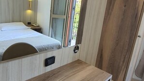 A room with a bed, a desk, and a TV mounted on the wall. - Hotel Mondial (Milan)