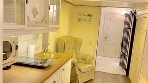 A kitchen with a wooden countertop, a sink, and a chair. There is a door with a black gate and a wall with pictures. - Apartment Fodorova 1 (Lviv)
