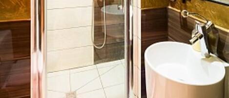 A bathroom with a glass-enclosed shower, a round sink, and a mirror above it.