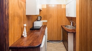 Eine kleine Küche mit Holzwänden, einer Holz Arbeitsplatte, einem Toaster, einem Wasserkocher, einer Spüle und einer Waschmaschine.