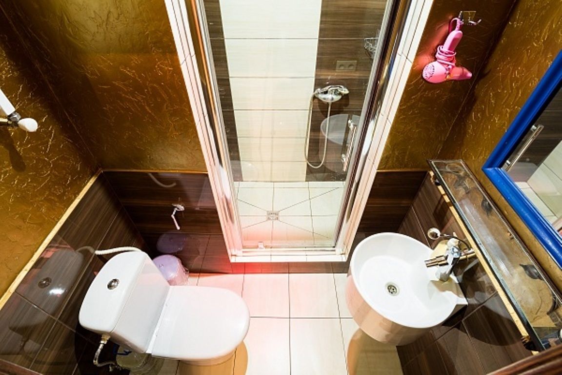 A modern bathroom with a glass-enclosed shower, two sinks, and a toilet.