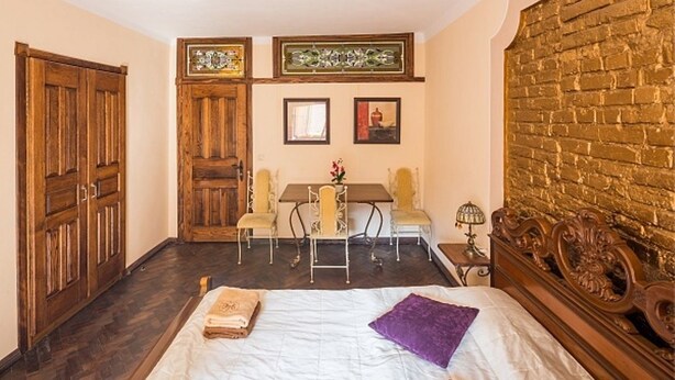 Ein Zimmer mit einem Bett, einem Holzschrank, einem Esstisch mit Stühlen und einer Backsteinwand.