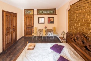 A room with a bed, wooden wardrobe, a dining table with chairs, and a brick wall. - Apartment Halytska 9b (Lviv)