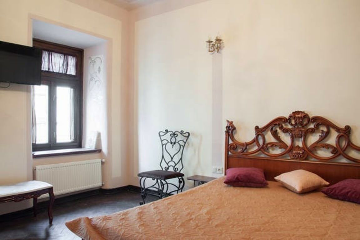 A bedroom with a bed, a chair, a window, and a radiator.
