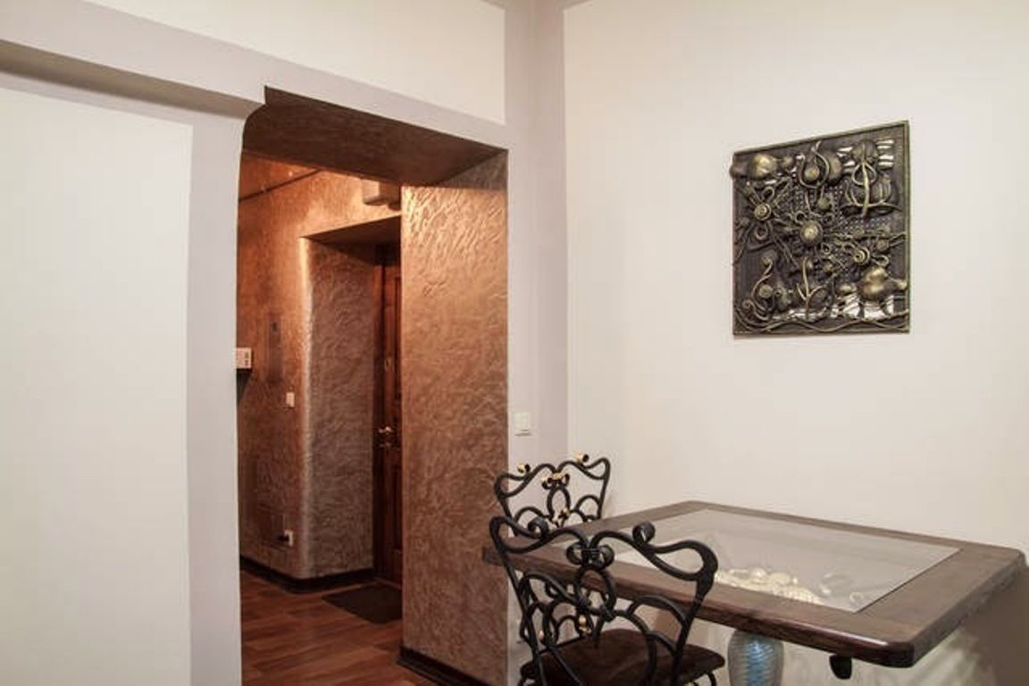 A dining area with a table and chairs, a decorative wall piece, and a textured wall.