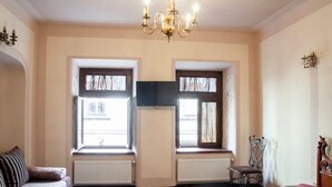 A bedroom with a bed, two windows, a radiator, a chair, and a chandelier. - Apartment Virmenska 14 (Lviv)
