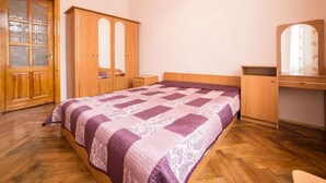 A bedroom with a wooden bed, a wardrobe, a mirror, and a door. - Economy Apartment Kopernika 9 (Lviv)