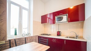 Una cocina compacta con gabinetes rojos, un microondas, una estufa a gas y un lavamanos.