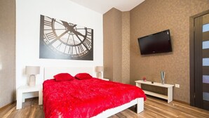 Un dormitorio moderno con una cama grande, un televisor montado y un reloj de pared.