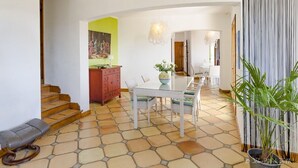 Un coin repas avec une table et des chaises, un escalier et une plante en pot.