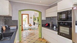 Une cuisine moderne avec des meubles blancs, un plan de travail noir et un four Bosch.