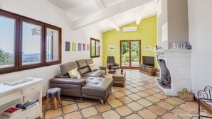 Un salon spacieux doté d’une grande fenêtre, d’une cheminée et offrant une vue sur l’extérieur.