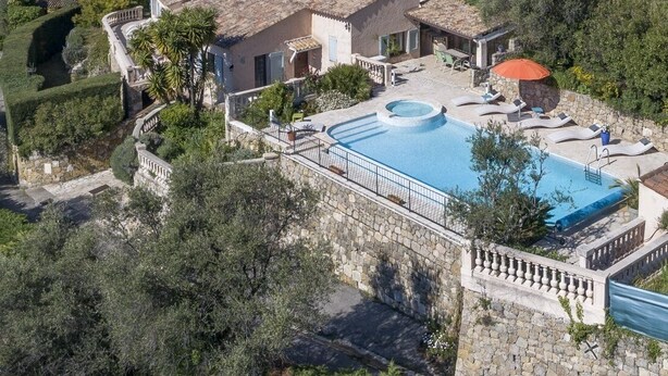 Une villa avec piscine, des murs en pierre et un jardin.