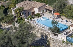 Une villa avec piscine, des murs en pierre et un jardin.