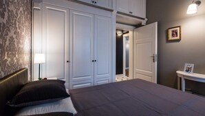 A bedroom with a large bed, a wardrobe, and a bedside table with a lamp.