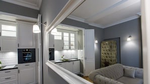 A modern kitchen with white cabinets, a built-in oven, and a large mirror reflecting the room.