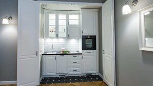 A compact kitchen with white cabinets, a black oven, and a tiled backsplash.