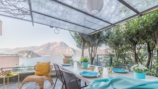 Een terras met een eettafel, met uitzicht op een waterpartij en bergen.