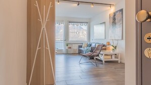 Een moderne woonkamer met een houten vloer, een bank, een stoel en een tafeltje met een lamp.