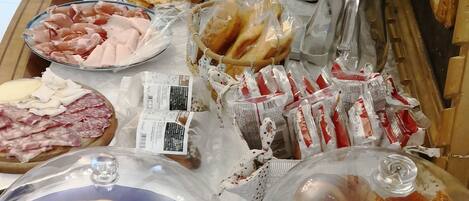 A buffet table with various food items, including meats, cheeses, and pastries.