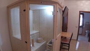 A wooden sauna with a bench, a small table, and a chair. - Alle Vecchie Mura (Pistoia)