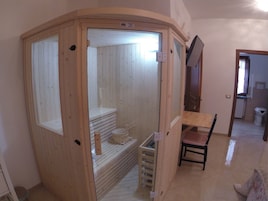 Una sauna de madera con un banco, una mesita y una silla.