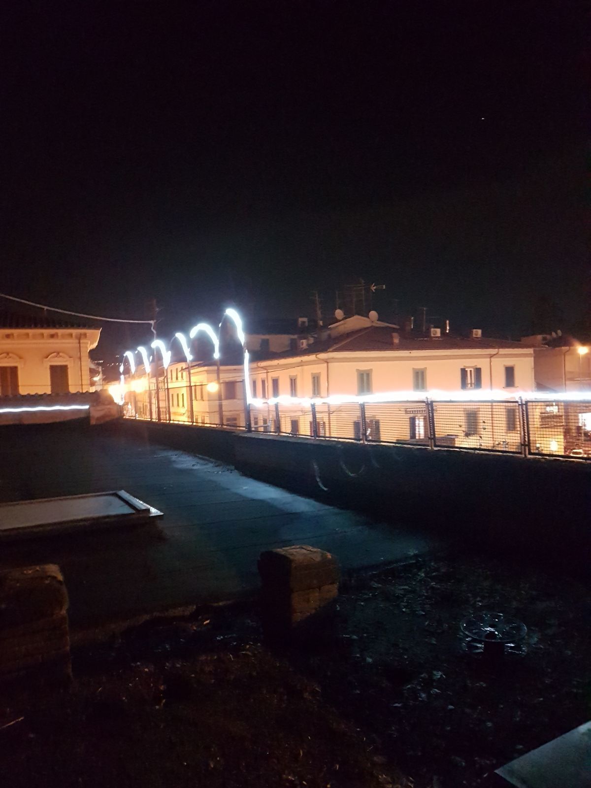 A nighttime view of a waterfront area with buildings and a bridge.