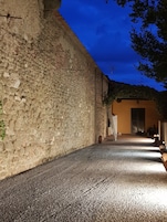 Un estrecho callejón con un muro de piedra a un lado y la entrada de un edificio al otro.