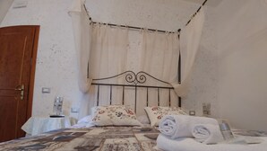 A bedroom with a bed, a wooden door, a nightstand, and a window with curtains. - Alle Vecchie Mura (Pistoia)