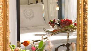 A bedroom with a bed, a mirror, and a window with sheer curtains. - Als Mansion by K&K (Oia)