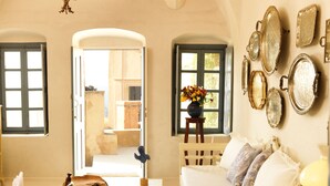 A cozy room with a wooden table, a white sofa, and a wall adorned with mirrors. - Als Mansion by K&K (Oia)