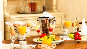 A breakfast setting with a coffee maker, glasses of orange juice, and a variety of breakfast items on a wooden table. - Als Mansion by K&K (Oia)