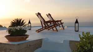 A beach setting with lounge chairs, a potted plant, and two lanterns. - Als Mansion by K&K (Oia)