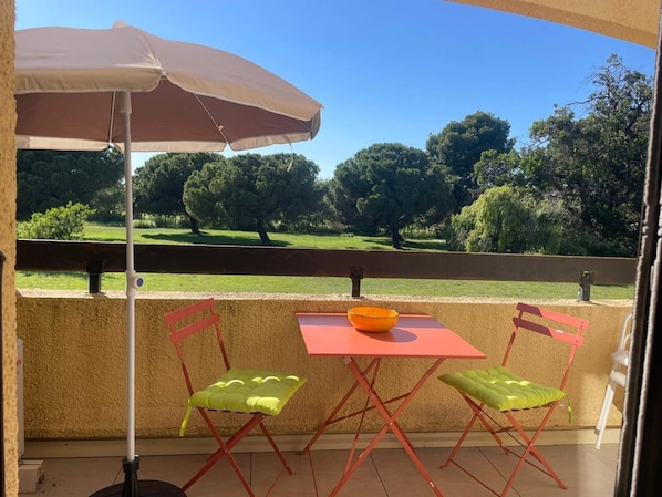 A balcony with a table, chairs, and an umbrella.