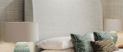 A neatly arranged bedroom with a bed, pillows, a vase, and a lamp.