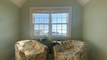 Enjoy the serene sea view from the large window, surrounded by a potted plant and two comfortable chairs.