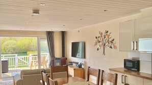 Cozinha moderna com armários de madeira, micro-ondas e área de refeições com mesa e cadeiras de madeira.