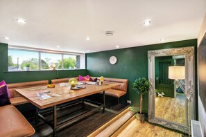 Un comedor moderno con una mesa de madera, asientos de cuero y un espejo grande.